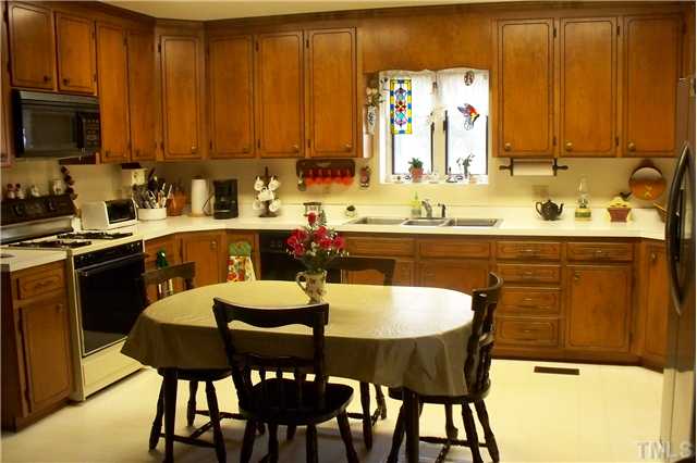 Eat in country kitchen with gas log fireplace and sitting area. Door beside refrigerator to sunroom