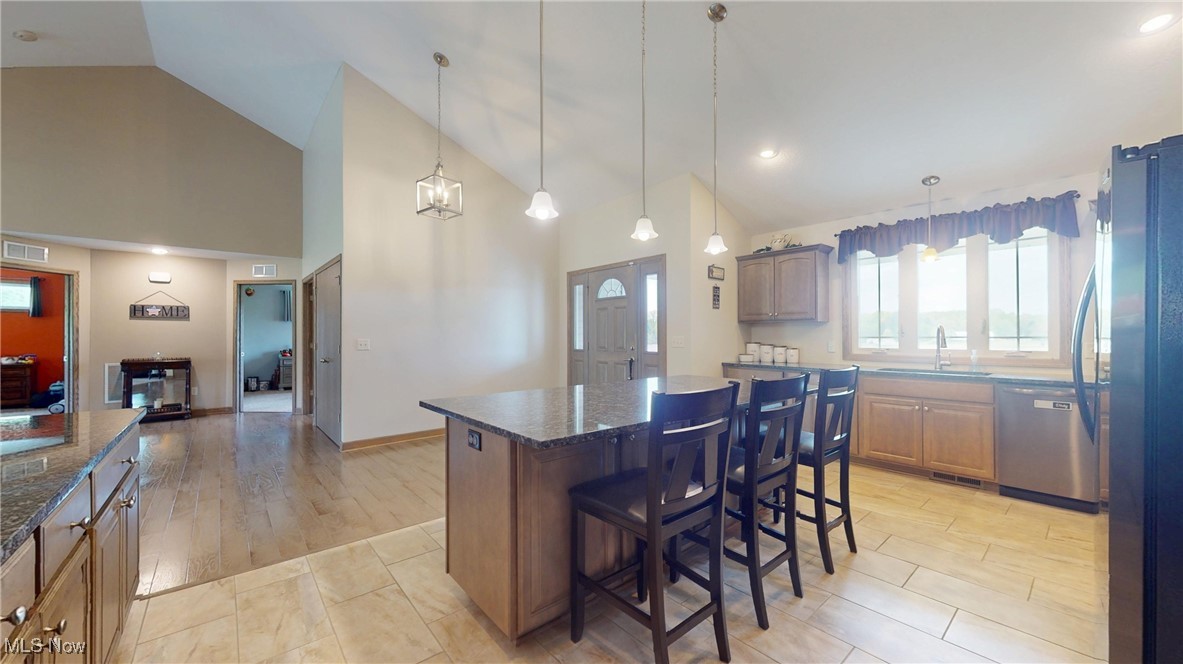 961 Industry Road Atwater, OH 44201 - Photo 7 of 50 Kitchen featuring appliances with stainless steel finishes, a kitchen island, dark stone countertops, a breakfast bar, and high vaulted ceiling