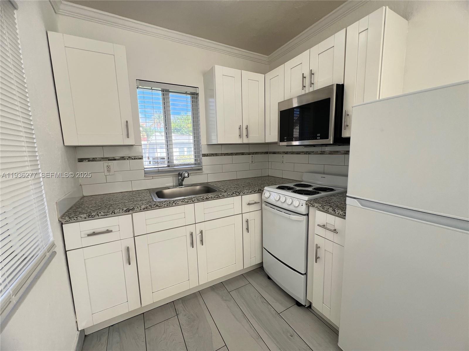 159 Northeast 75th Street, Unit 1 Miami, FL 33138 - Photo 2 of 8 a kitchen with stainless steel appliances granite countertop white cabinets granite counter tops and a window