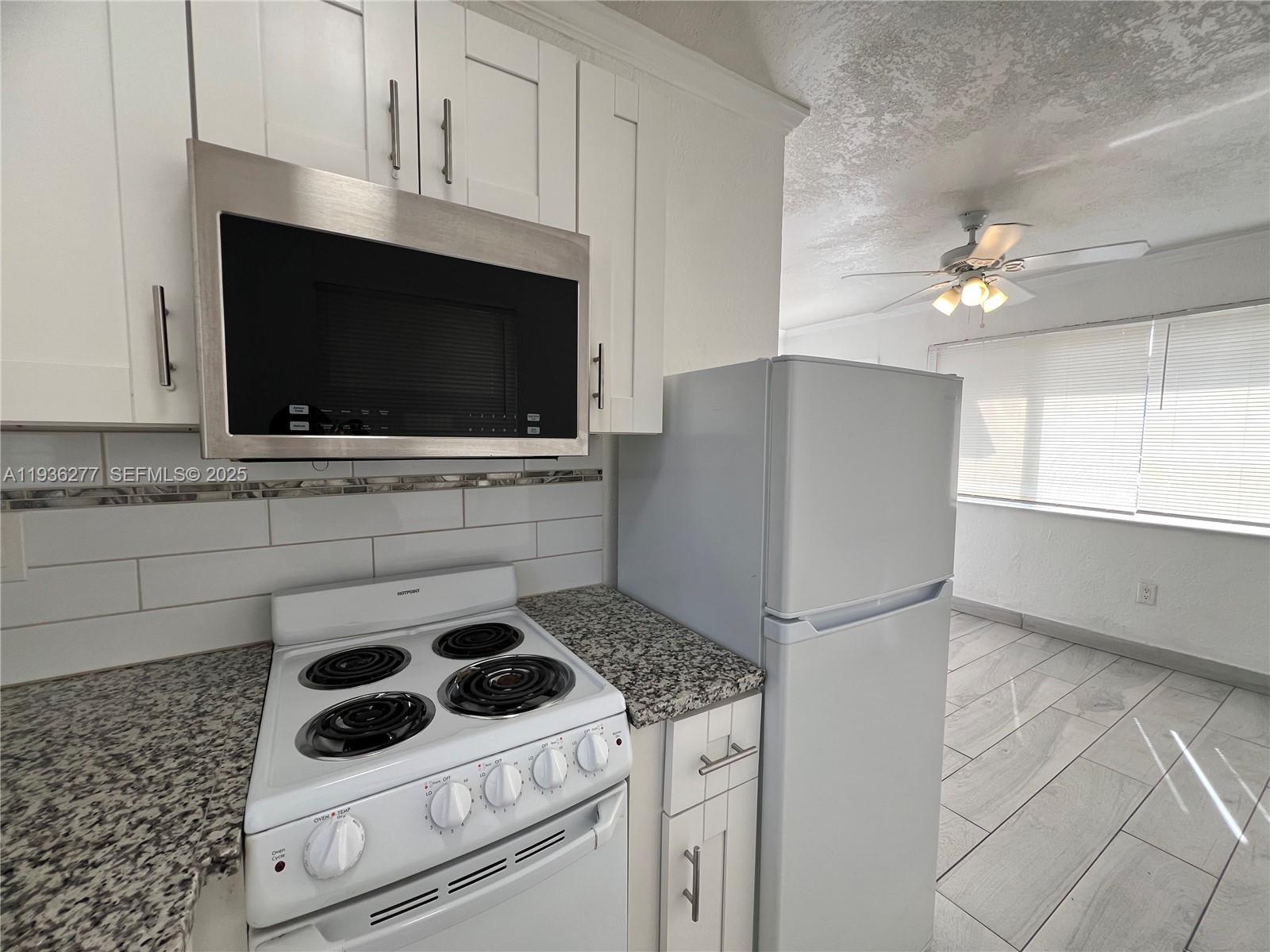 159 Northeast 75th Street, Unit 1 Miami, FL 33138 - Photo 8 of 8 a kitchen with a stove a microwave and cabinets