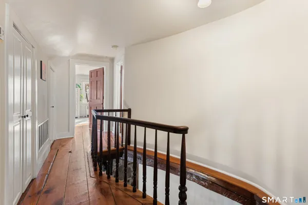 a view of a hallway with wooden floor and staircase