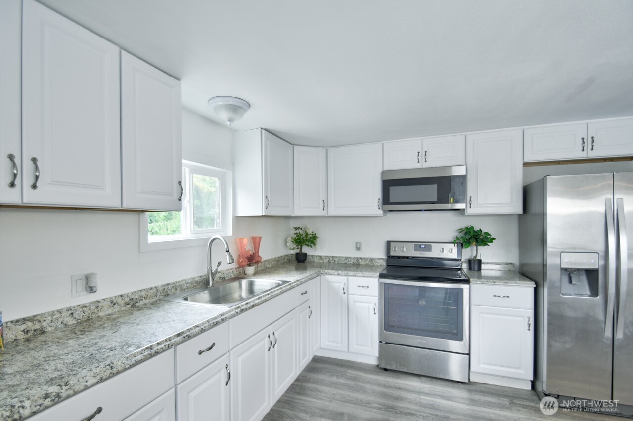 15503 Cedar Park Road Southeast, Unit 14 Olalla, WA 98359 - Photo 4 of 14 a kitchen with granite countertop white cabinets white stainless steel appliances and sink