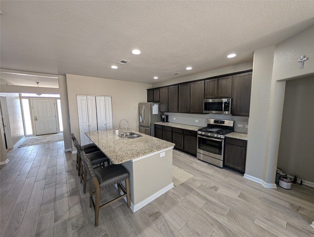 1269 Nevarez Kyle, TX 78640 - Photo 4 of 30 a kitchen with stainless steel appliances kitchen island granite countertop a refrigerator oven a sink dishwasher and a stove with wooden floor
