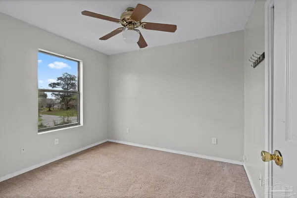 an empty room with windows and fan