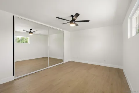 an empty room with windows and fan