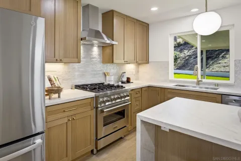 a kitchen with stainless steel appliances a stove a sink cabinets and a window