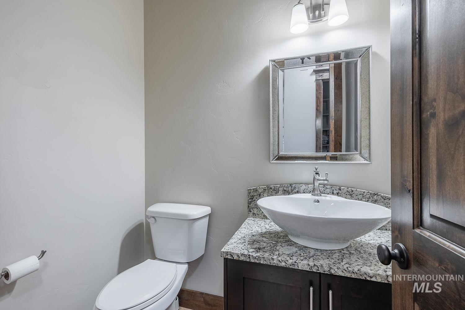 8077 Star Pass Ridge Road Nampa, ID 83686 - Photo 20 of 37 Bathroom featuring a vessel sink, speckled countertop, and wood-finish cabinetry