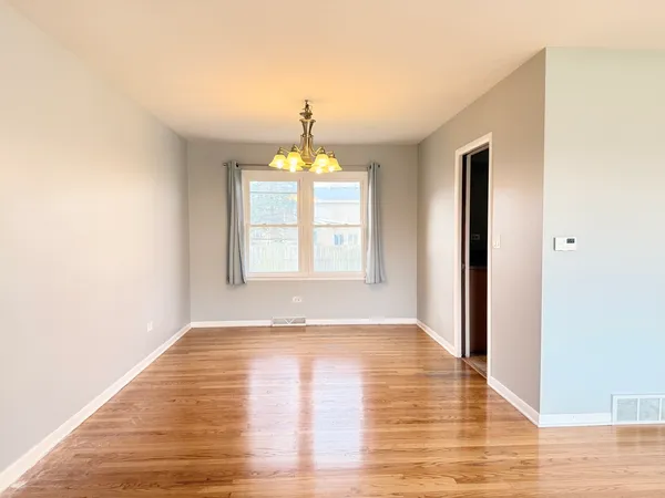 a view of an empty room with wooden floor and fan