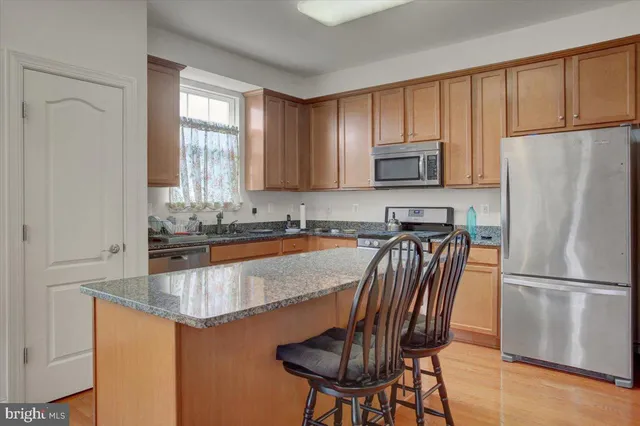 a kitchen with granite countertop a refrigerator a stove a sink cabinets and a dining table