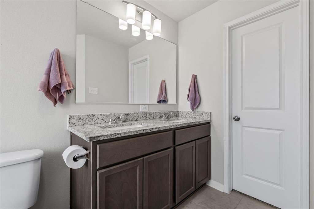 4056 Centerfire Road Waco, TX 76705 - Photo 17 of 27 a bathroom with a granite countertop sink a toilet and a mirror