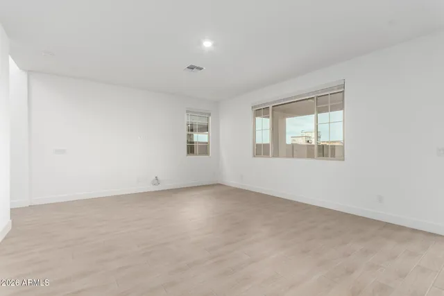 a view of an empty room with a window and wooden floor