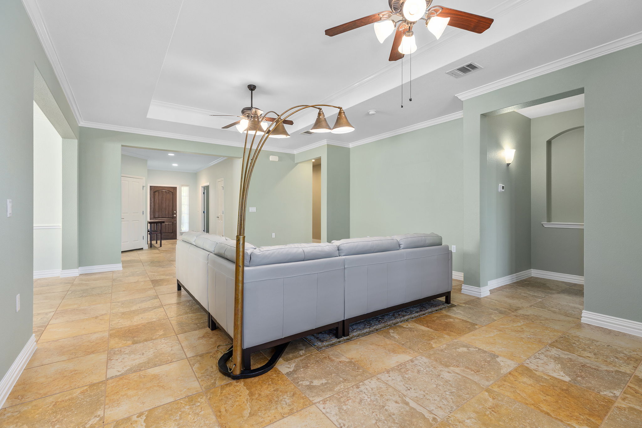 110 Emory Peak Trail Georgetown, TX 78633 - Photo 13 of 39 Living room with a tray ceiling, ceiling fan, ornamental molding, and stone tile floors