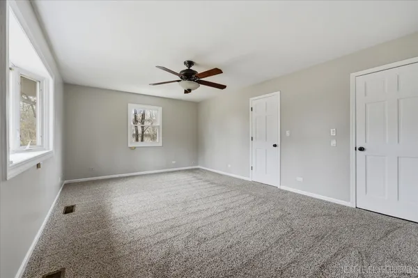 an empty room with wall ceiling fan and window