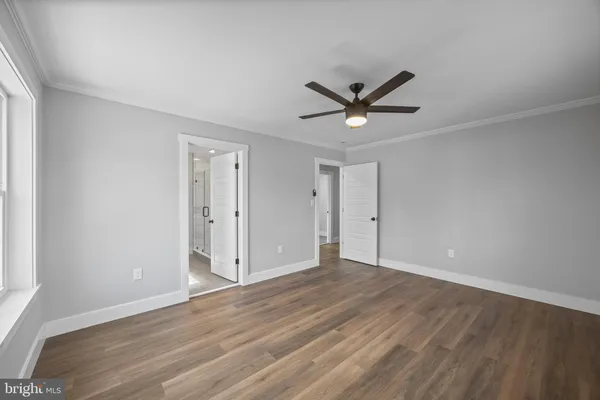 an empty room with wooden floor and ceiling fan