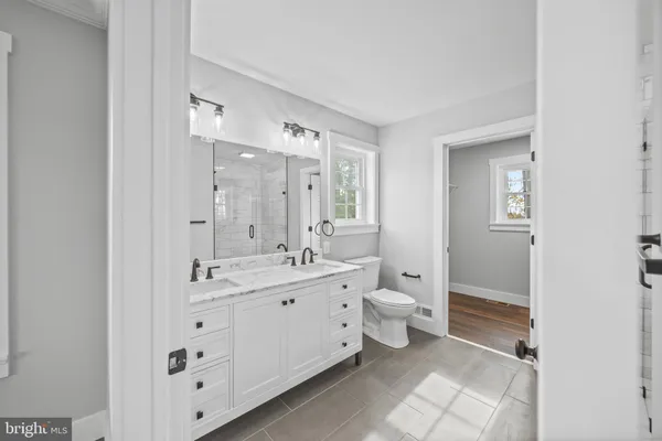 a spacious bathroom with double sink a toilet and a mirror
