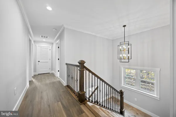 a view of a hallway with wooden floor and chandelier