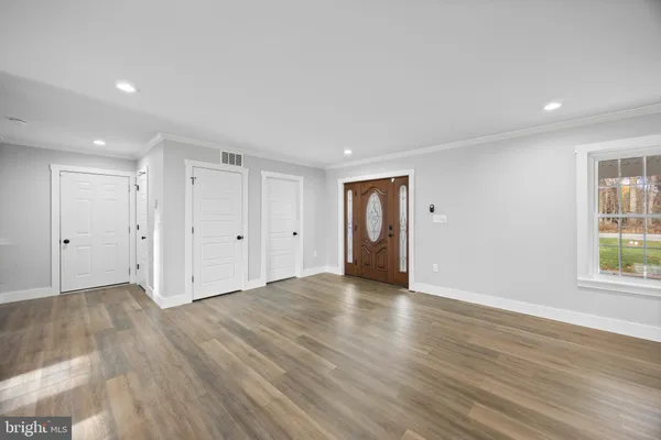 a view of an empty room with wooden floor and windows