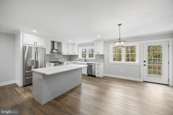 a large kitchen with kitchen island a large counter top space a sink stainless steel appliances and cabinets