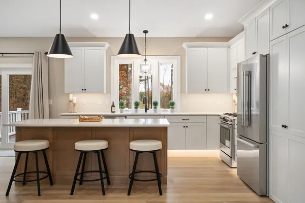 a kitchen with stainless steel appliances a sink a stove a refrigerator and chairs