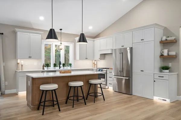 a kitchen with stainless steel appliances a dining table chairs refrigerator and microwave