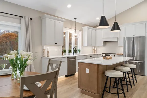 a kitchen with stainless steel appliances a sink a stove a refrigerator a dining table and chairs
