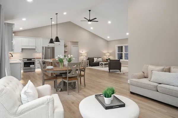 a living room with furniture kitchen view and a chandelier