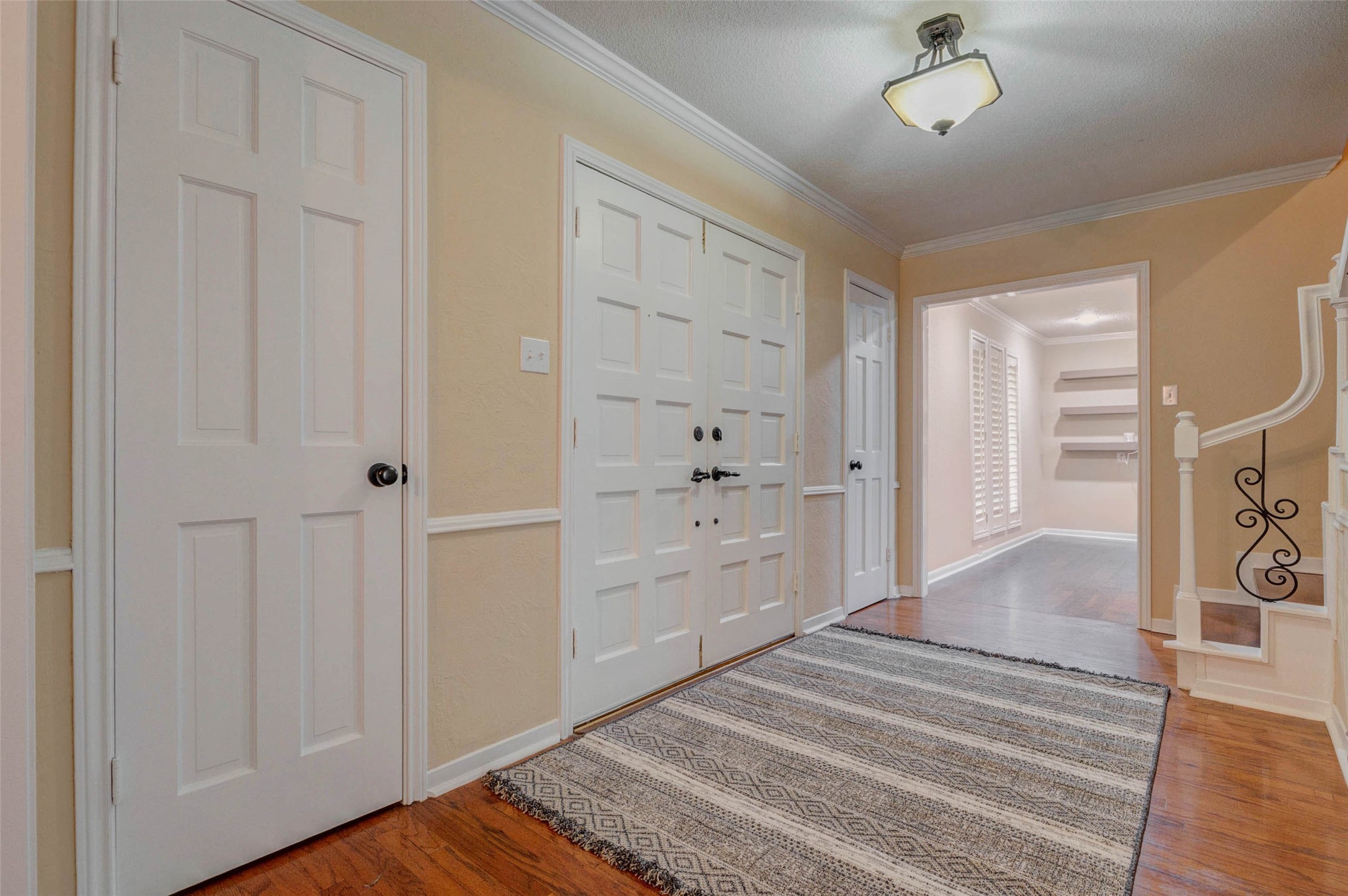 6710 Falling Waters Drive Spring, TX 77379 - Photo 8 of 46 This welcoming entryway features warm-toned walls and hardwood flooring. It includes a central light fixture, multiple doors, and a staircase with decorative iron balusters. A hallway leads to additional living spaces.