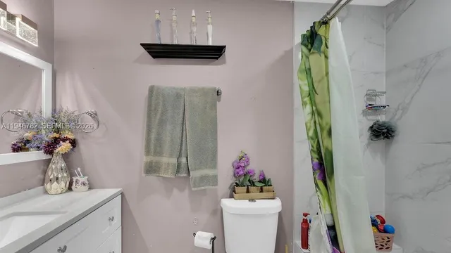 a bathroom with a granite countertop sink a vanity and a shower curtain