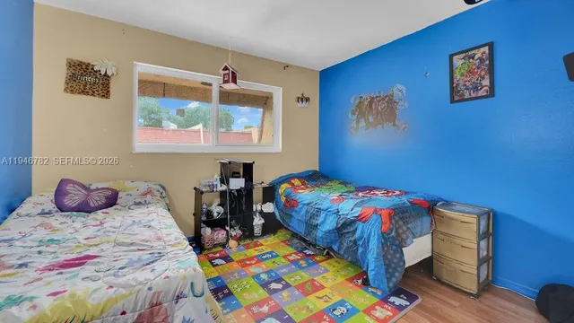 a bedroom with a bed a dresser and painting on the wall