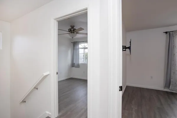 an empty room with wooden floor fan and windows