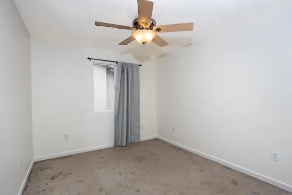 an empty room with closet and a chandelier fan