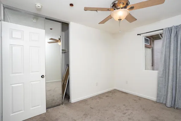 a view of empty room with windows and ceiling fan
