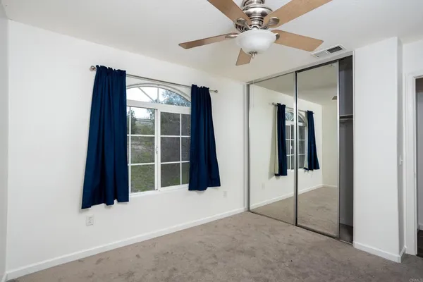 an empty room with windows and fan