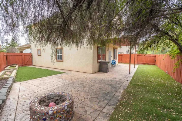 a view of a backyard with large trees and wooden fence