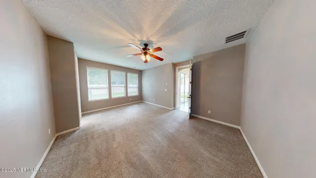 an empty room with chandelier fan and windows
