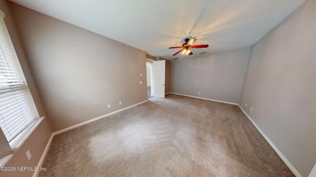 an empty room with windows and ceiling fan