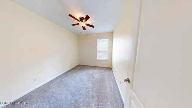 an empty room with windows and fan