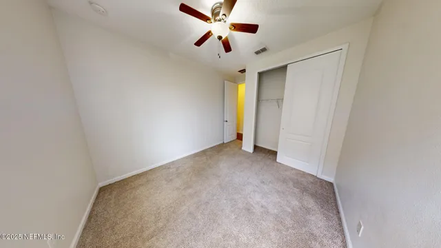 a view of an empty room and a ceiling fan