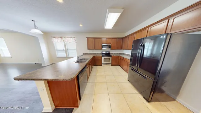 a kitchen with stainless steel appliances granite countertop a refrigerator a sink a stove and cabinets