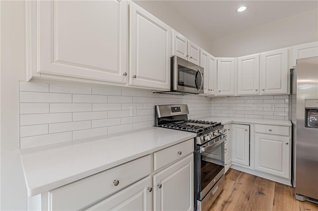 775 Southland Pass Stone Mountain, GA 30087 - Photo 24 of 76 a kitchen with stainless steel appliances white cabinets and a stove a oven with white countertops