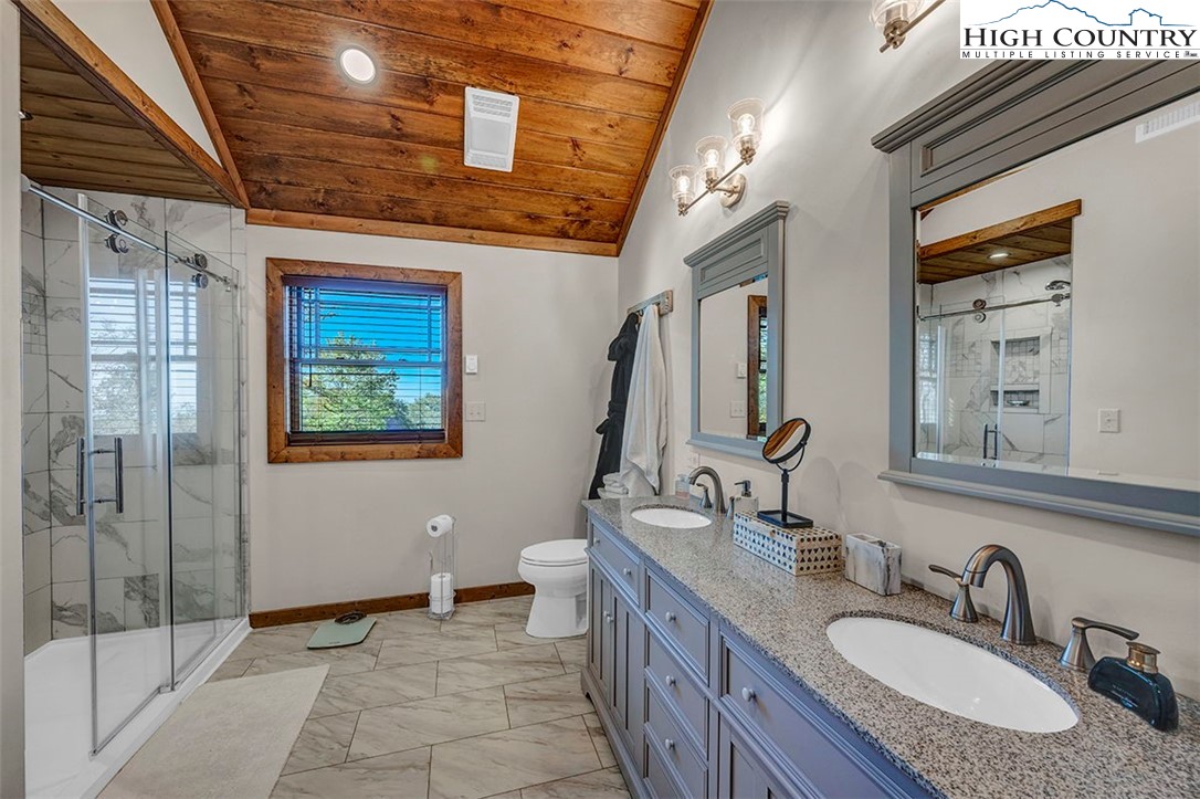 428 Cloud Spring Drive Sugar Mountain, NC 28604 - Photo 37 of 45 a bathroom with a granite countertop sink a mirror a vanity and a shower