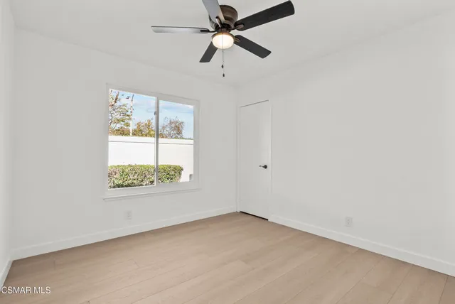 an empty room with a window and a fan