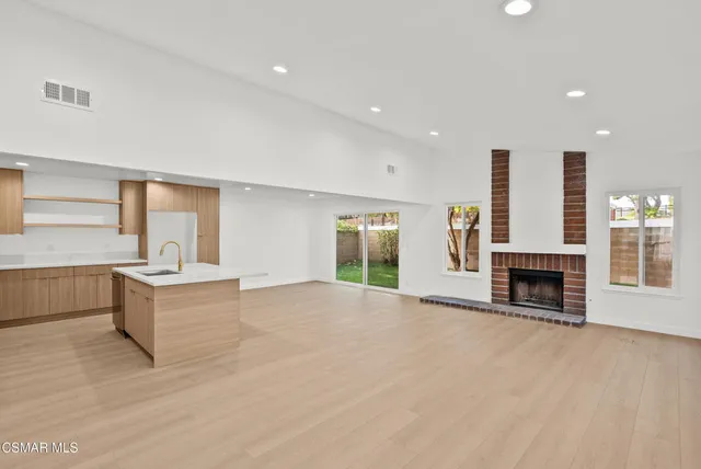 a large white kitchen with granite countertop a stove and a sink with granite countertops