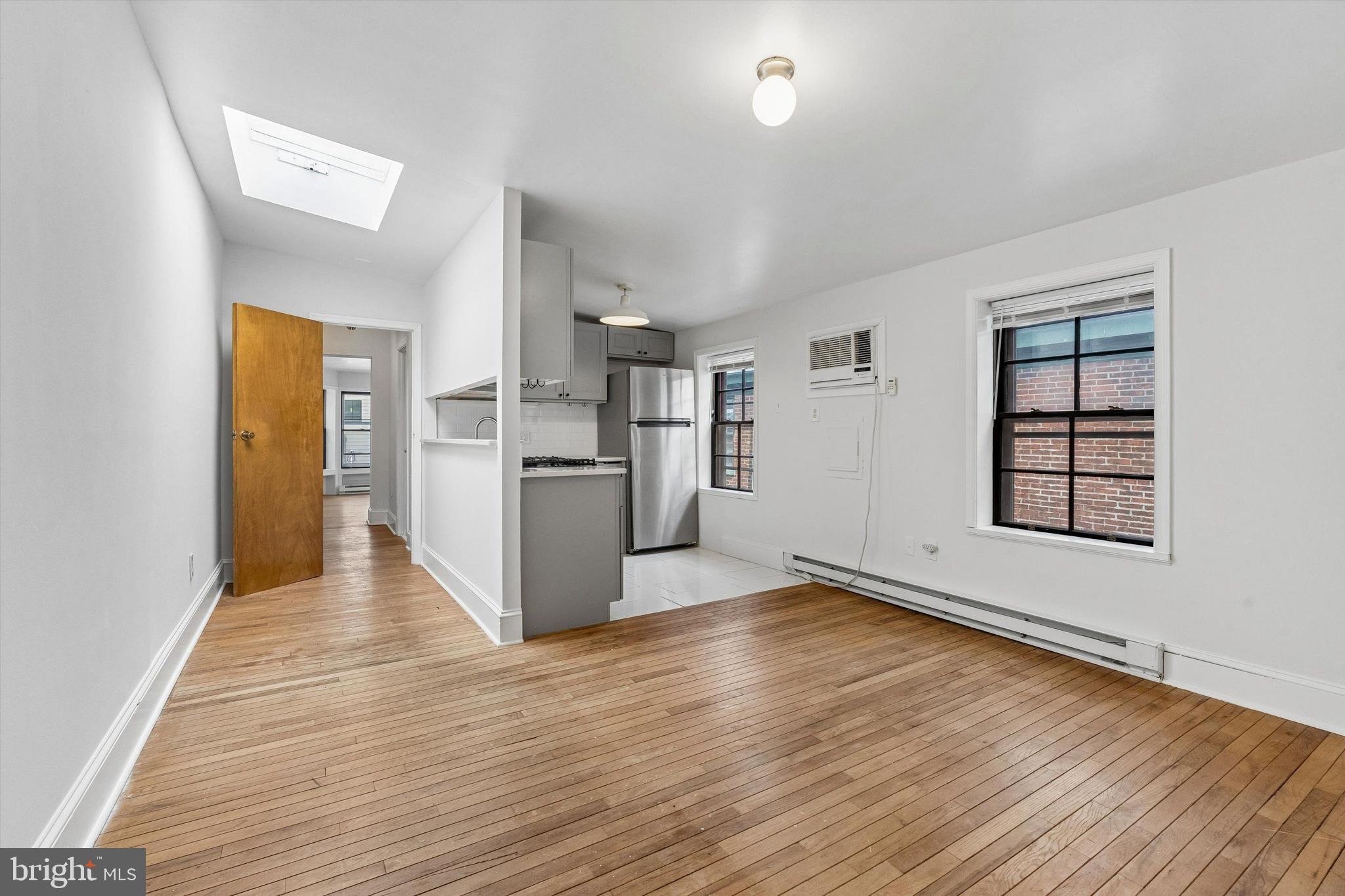 2105 Green Street, Unit 3R Philadelphia, PA 19130 - Photo 4 of 11 an empty room with wooden floor and a kitchen