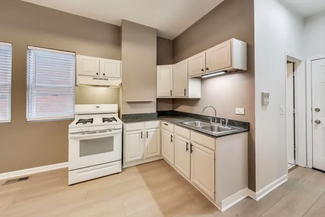 a kitchen with stainless steel appliances a white stove top oven and white cabinets