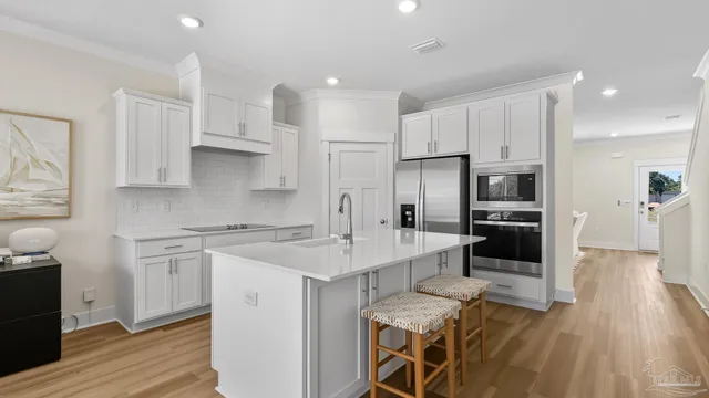 a kitchen with stainless steel appliances a sink a stove a refrigerator cabinets and wooden floor