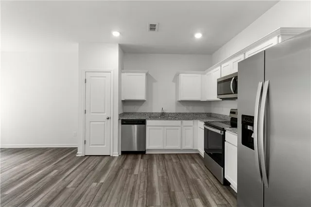 a kitchen with granite countertop stainless steel appliances a sink and refrigerator