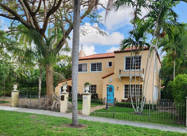 a view of a white house next to a yard with big trees