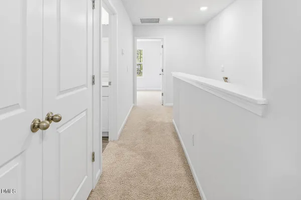 a view of a hallway with wooden floor and a bathroom