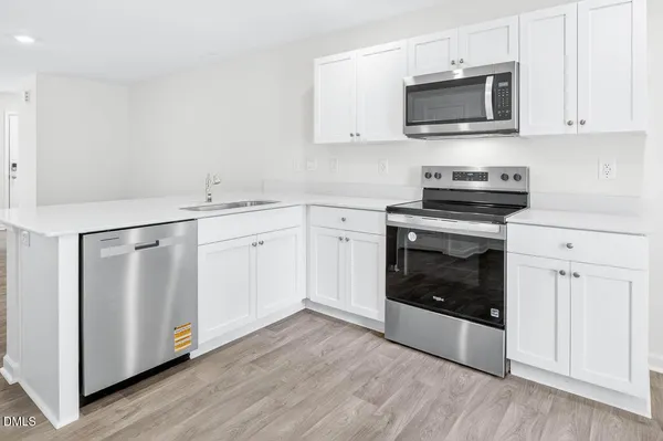 a kitchen with cabinets stainless steel appliances a sink and wooden floor